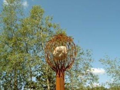 Skulptur aus Metall geformter Baum mit Stein in der Krone