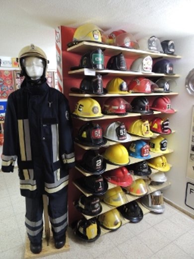 Feuerwehrsammlung, Helme und Anzüge in Regalen an der Wand