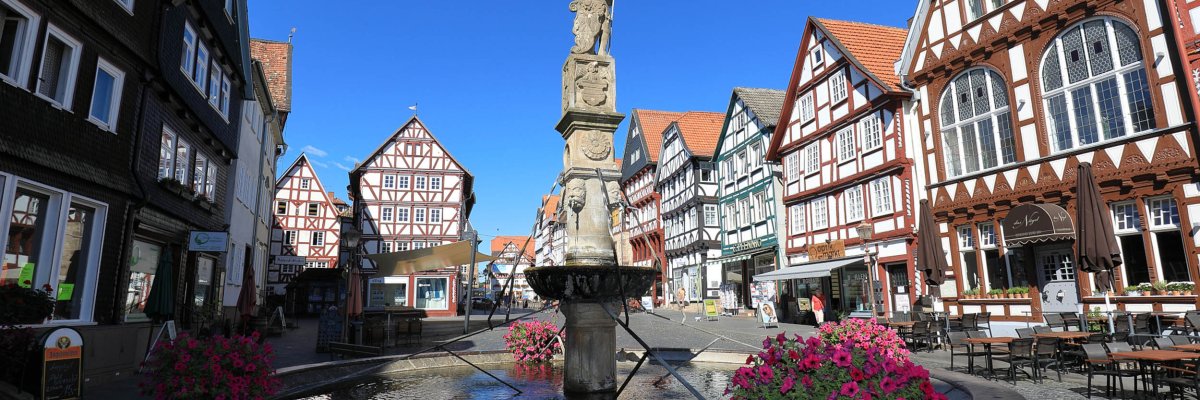 Sicht auf Fachwerkfassaden des Fritzlarer Marktplatzes. Zu sehen sind Gebäude mit rötlich oder schwarz bemaltem Fachwerk und weiß verputzen Gefachen.